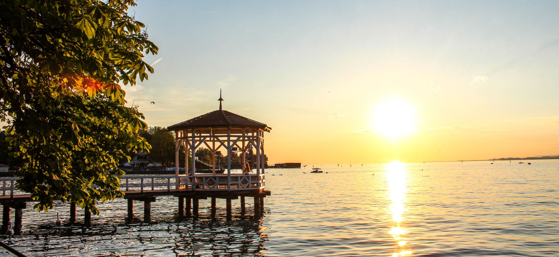 Bodenseeschifferpatent Kosten – Sonnenuntergang über dem Bodensee mit Booten im Hintergrund