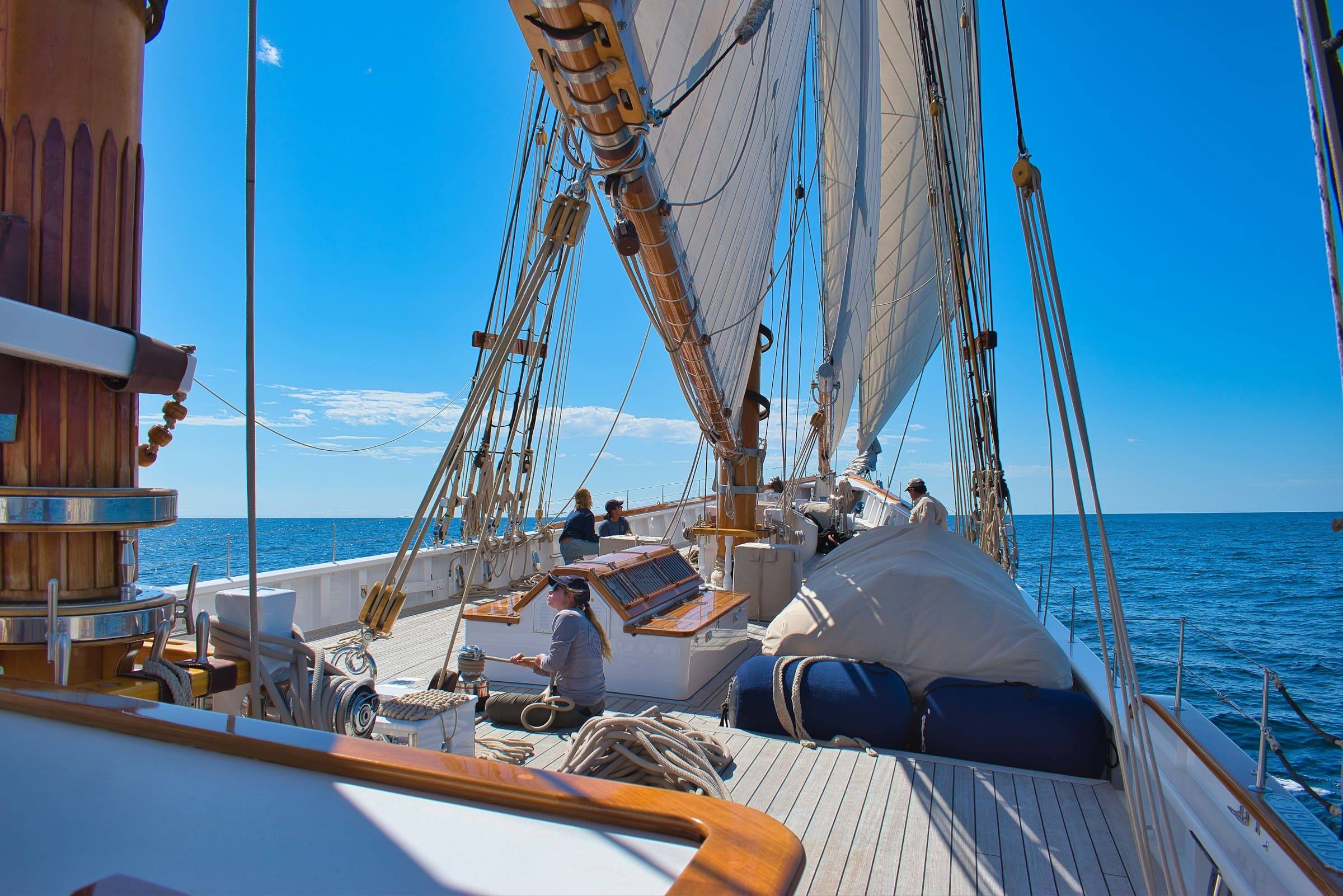 Crew auf einem großen Segelschiff trainiert mit gesetzten Segeln auf dem Meer – Praxis für den Bootsführerschein.