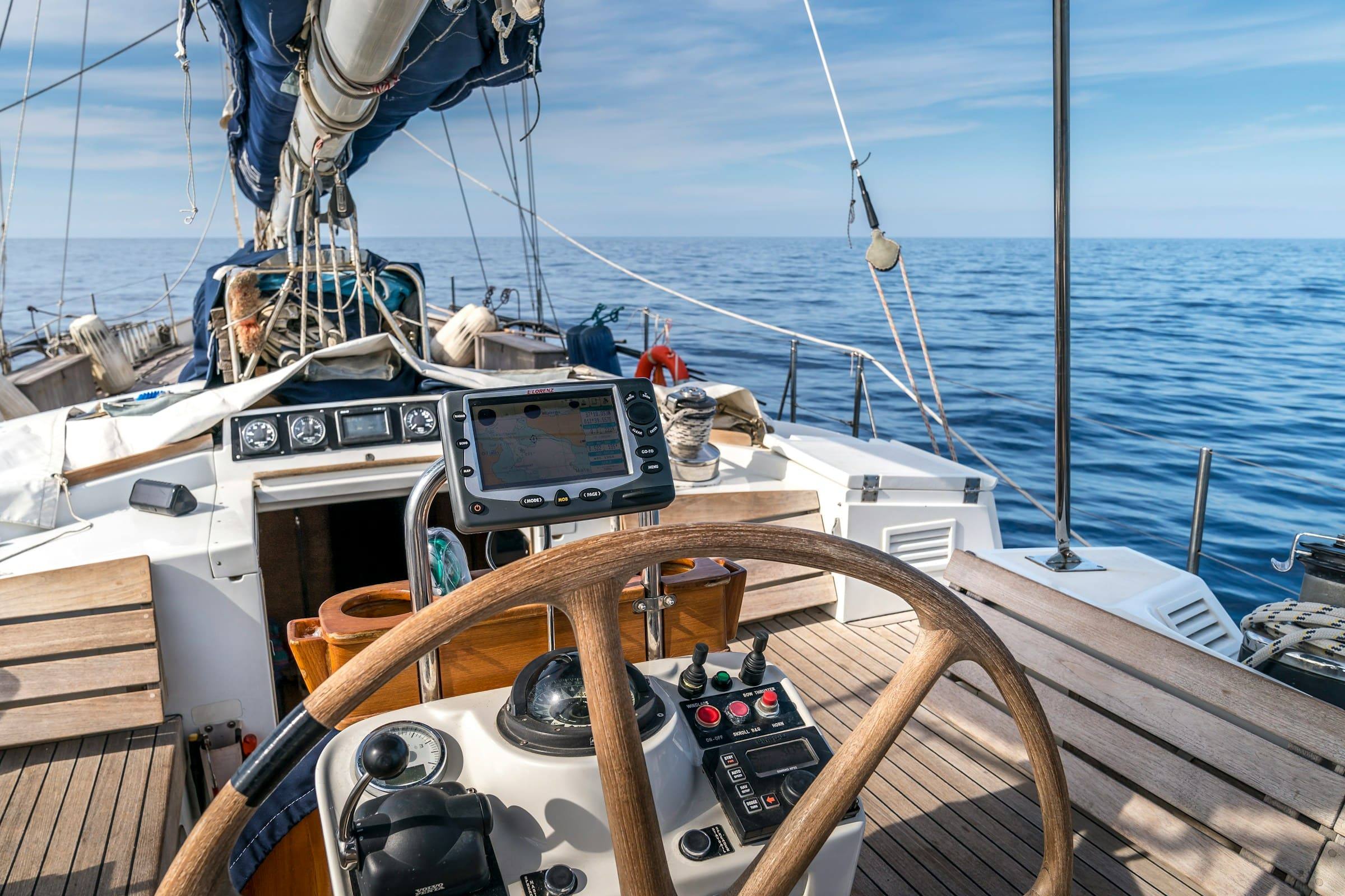 Steuerstand einer Segelyacht mit Steuerrad, Navigationsinstrumenten und Blick aufs offene Meer.