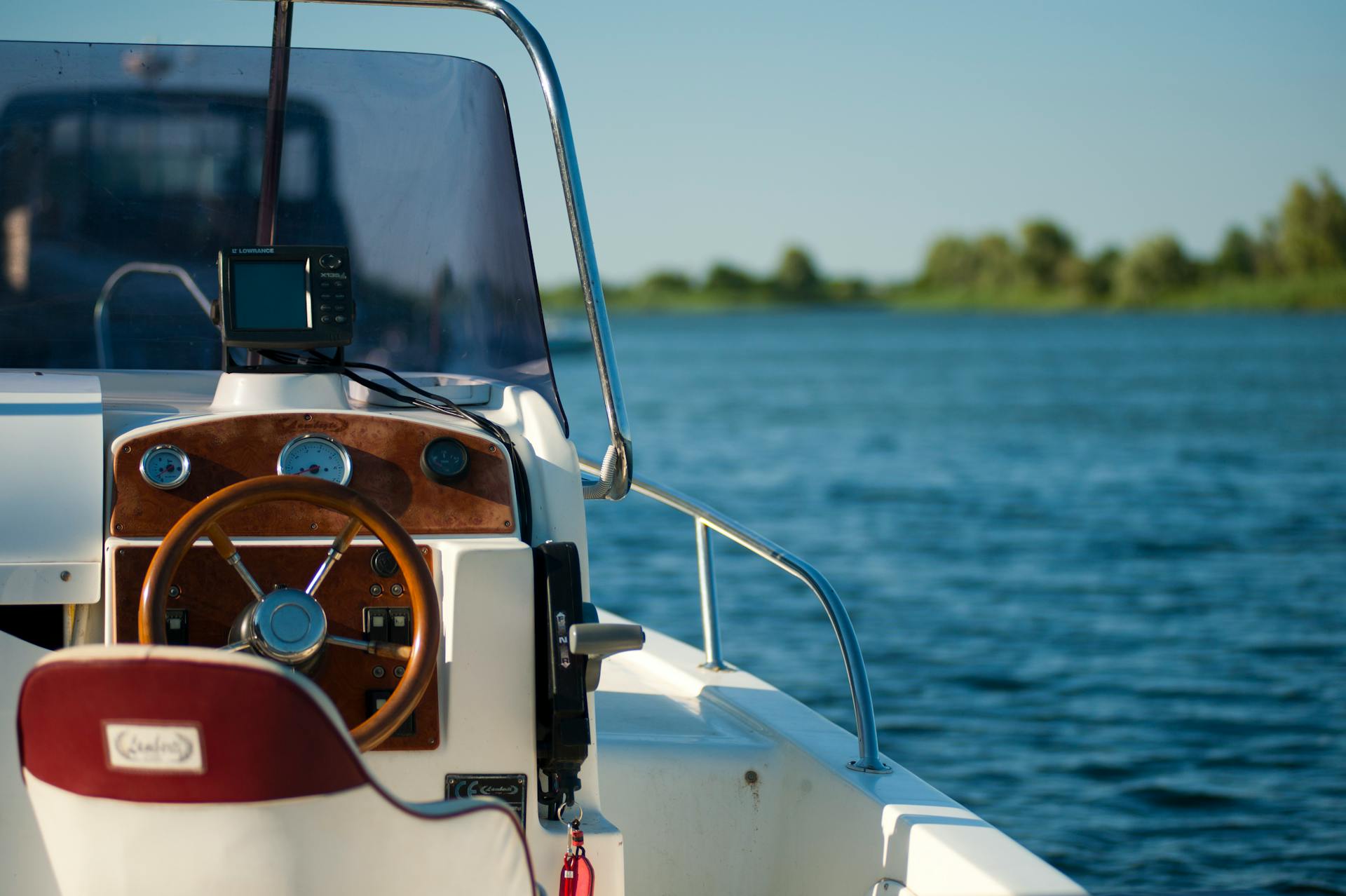 Steuerstand eines Motorbootes mit Holzlenkrad und Navigationsinstrumenten auf einem See für die Bootsführerschein Praxisprüfung.