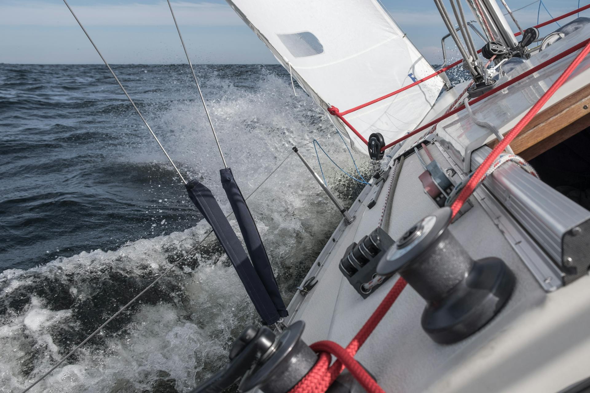 Krängende Segelyacht mit Wasserfontäne am Vorschiff – Seemannschaft und Manöverbeherrschung.
